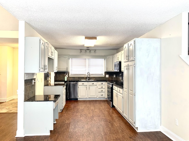 kitchen with dark wood-type flooring, appliances with stainless steel finishes, sink, and decorative backsplash