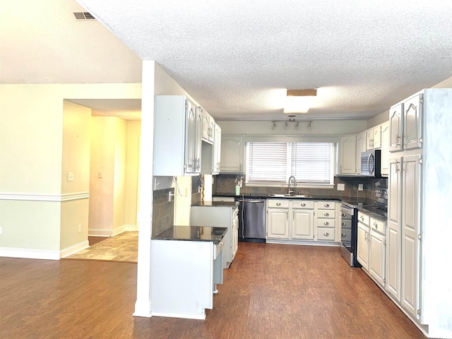 kitchen with sink, a textured ceiling, dark hardwood / wood-style floors, stainless steel appliances, and decorative backsplash