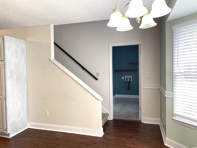 stairs featuring hardwood / wood-style flooring, an inviting chandelier, and a textured ceiling