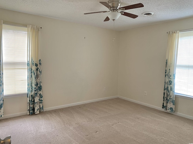 carpeted empty room featuring ceiling fan, a healthy amount of sunlight, and a textured ceiling