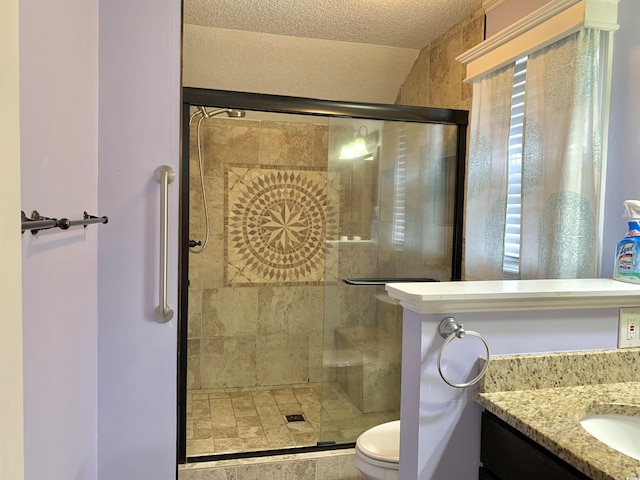 bathroom featuring vanity, a textured ceiling, a shower with shower door, and toilet