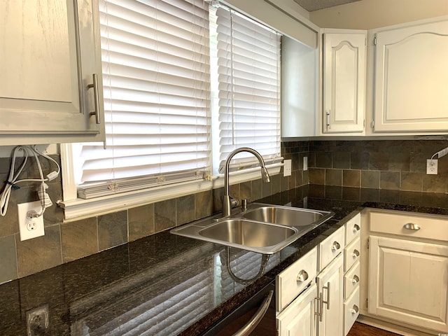 kitchen featuring sink, backsplash, dark stone counters, and white cabinets