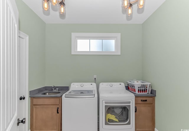 clothes washing area with cabinets, a notable chandelier, sink, and washing machine and clothes dryer