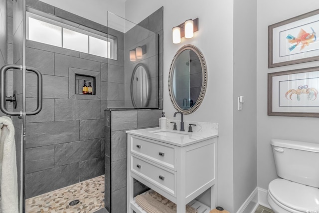 bathroom with a tile shower, vanity, and toilet