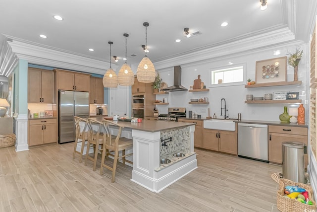 kitchen featuring a breakfast bar, sink, appliances with stainless steel finishes, a kitchen island, and wall chimney range hood