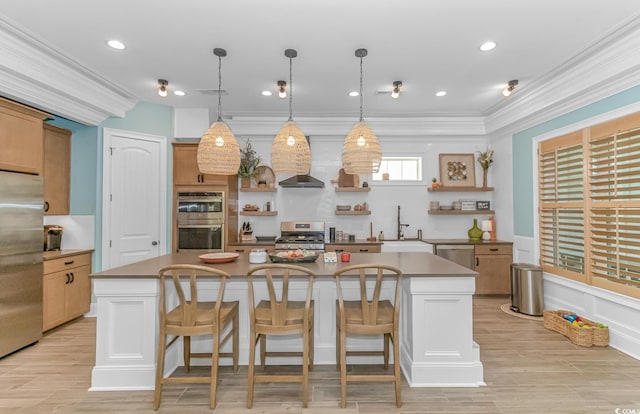 kitchen featuring appliances with stainless steel finishes, sink, a breakfast bar area, hanging light fixtures, and a center island