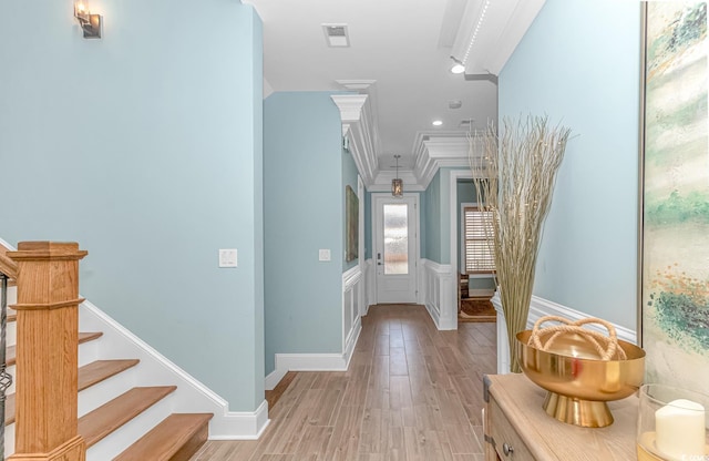 corridor with ornamental molding and light hardwood / wood-style floors