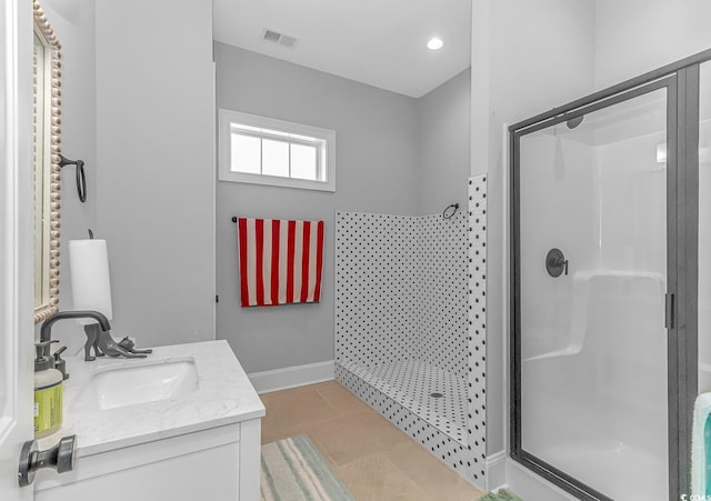 bathroom with a shower with door, vanity, and tile patterned flooring