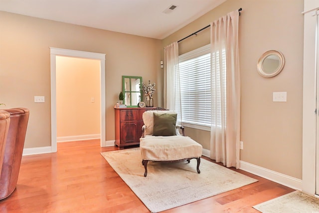 sitting room with visible vents, light wood-style flooring, and baseboards