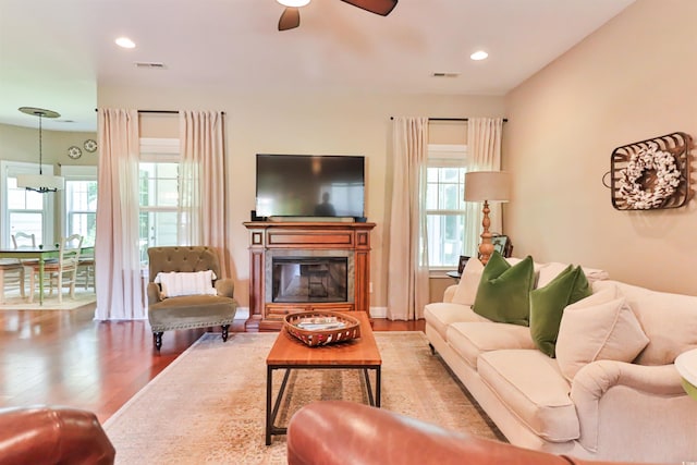 living room featuring recessed lighting, visible vents, wood finished floors, and a glass covered fireplace