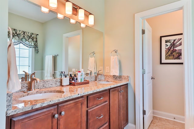 full bath with double vanity, tile patterned flooring, a sink, and baseboards