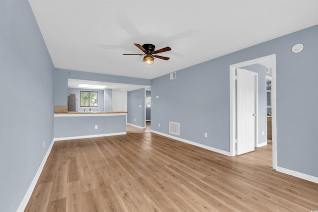 unfurnished living room featuring ceiling fan, sink, and light hardwood / wood-style flooring