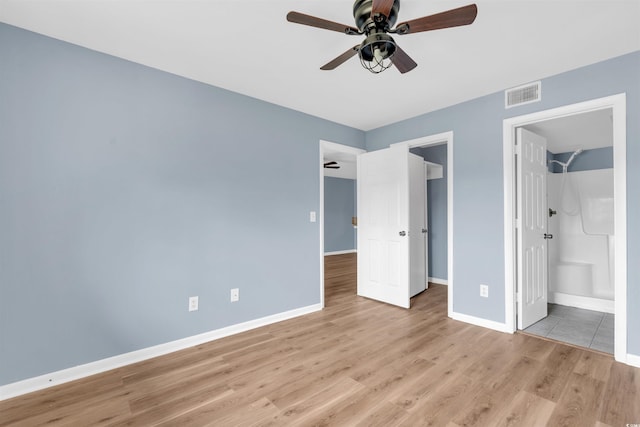 unfurnished bedroom with a walk in closet, ceiling fan, connected bathroom, and light hardwood / wood-style floors