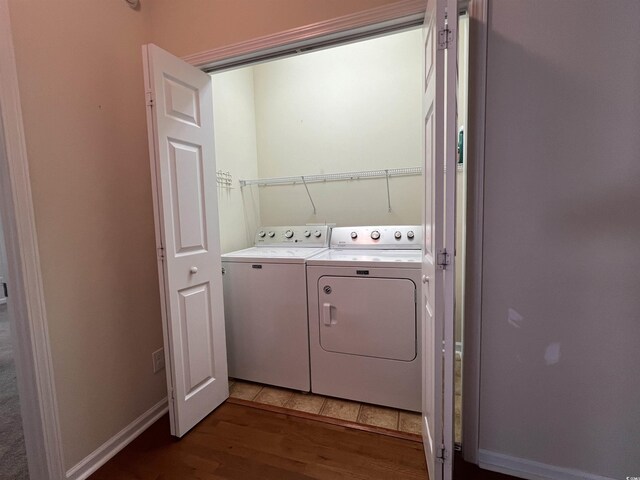 clothes washing area featuring washing machine and dryer and wood-type flooring