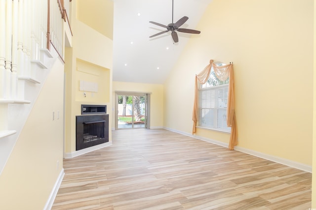 unfurnished living room featuring light wood-type flooring, high vaulted ceiling, and ceiling fan