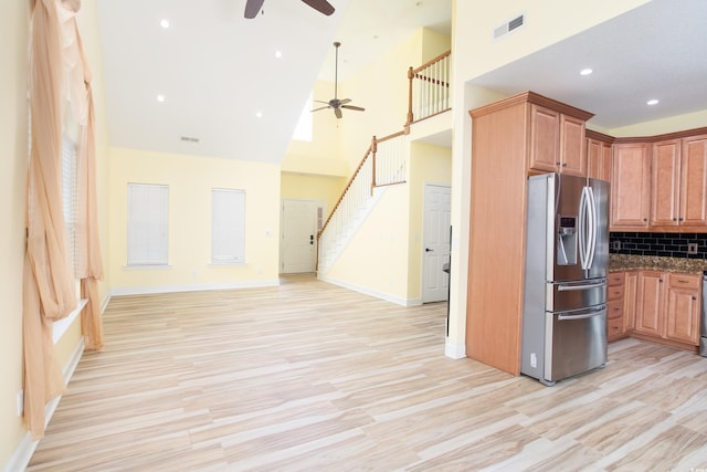 kitchen with high vaulted ceiling, visible vents, open floor plan, tasteful backsplash, and stainless steel fridge