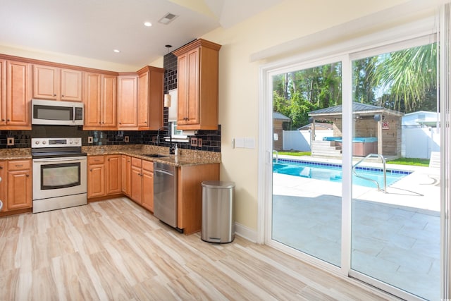 kitchen with stainless steel appliances, tasteful backsplash, visible vents, a sink, and dark stone countertops