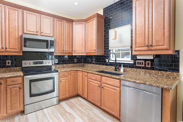 kitchen with stone counters, decorative backsplash, stainless steel appliances, and a sink