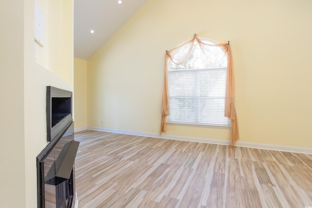 unfurnished living room featuring high vaulted ceiling, recessed lighting, wood finished floors, and baseboards