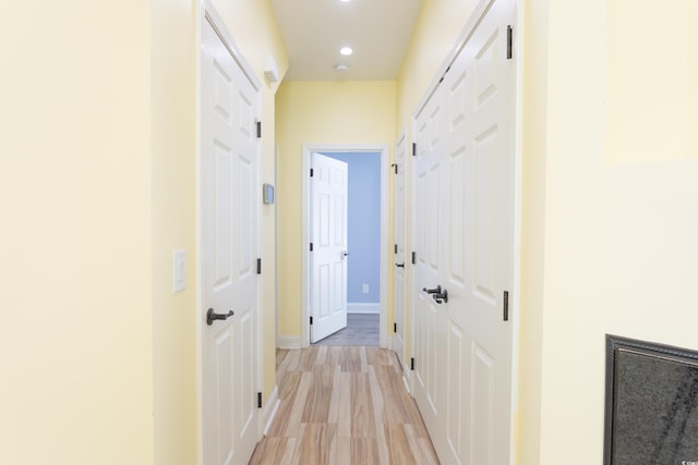 hallway featuring recessed lighting, baseboards, and light wood finished floors