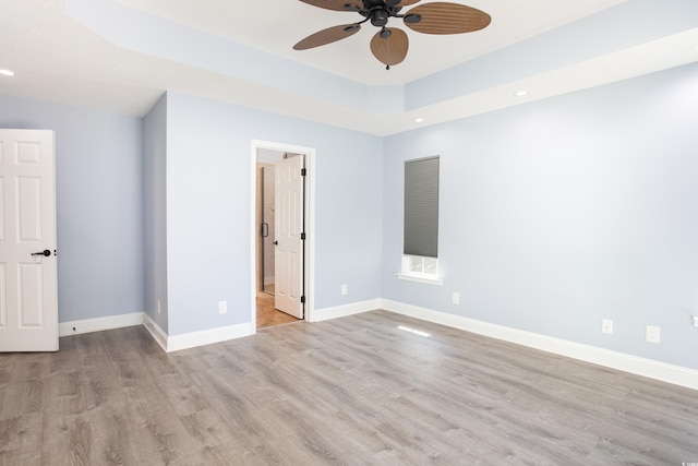 unfurnished bedroom with baseboards, a raised ceiling, wood finished floors, and recessed lighting