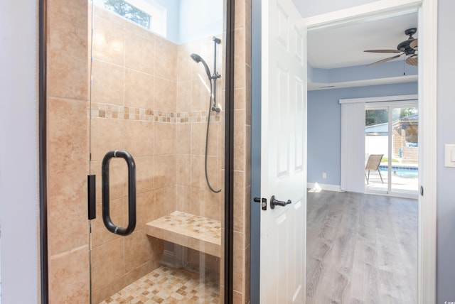 full bathroom featuring ceiling fan, wood finished floors, a shower stall, and baseboards