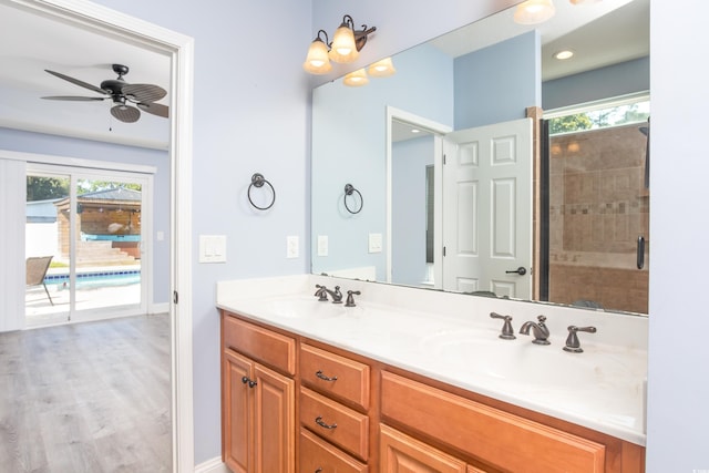 bathroom featuring a ceiling fan, wood finished floors, a sink, and double vanity