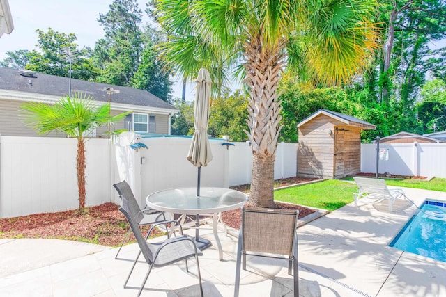 view of patio featuring a fenced in pool, an outbuilding, outdoor dining area, a shed, and a fenced backyard