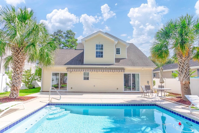 rear view of property featuring roof with shingles, fence, an outdoor pool, and a patio