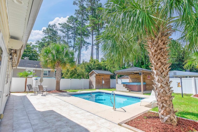 view of pool featuring a patio area, a hot tub, a fenced backyard, and an outdoor structure