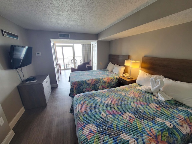 bedroom with dark hardwood / wood-style floors and a textured ceiling