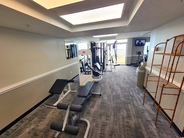 exercise room with a textured ceiling and dark colored carpet