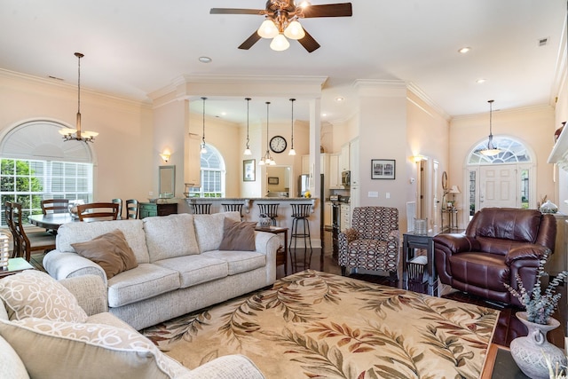 living room featuring ornamental molding, wood-type flooring, and ceiling fan with notable chandelier