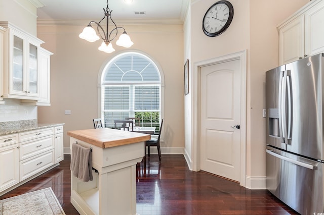 kitchen with light stone counters, an inviting chandelier, white cabinets, and stainless steel refrigerator with ice dispenser