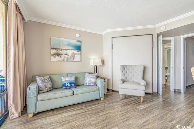 living room featuring wood-type flooring, a textured ceiling, and ornamental molding