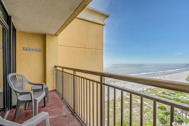 balcony with a water view and a view of the beach