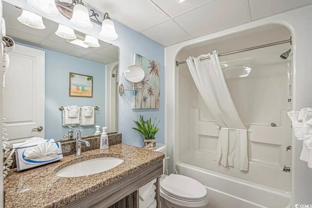 full bathroom featuring vanity, a drop ceiling, toilet, and shower / tub combo