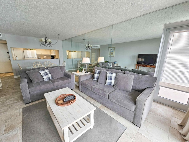 living room featuring a chandelier, a textured ceiling, and vaulted ceiling