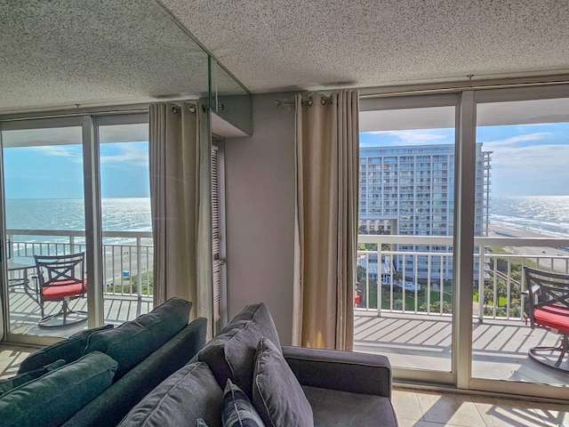 interior space featuring floor to ceiling windows, plenty of natural light, a water view, and a view of the beach