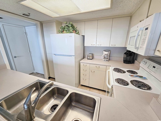 kitchen with light tile patterned floors, sink, white appliances, and white cabinetry