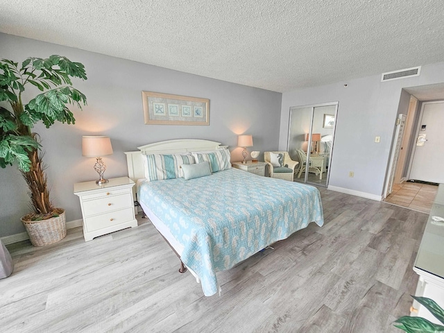 bedroom with a textured ceiling, light hardwood / wood-style floors, and a closet