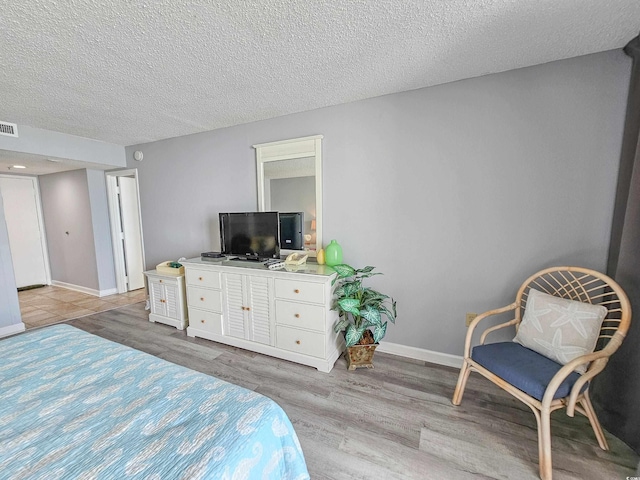 bedroom featuring a textured ceiling and light hardwood / wood-style flooring