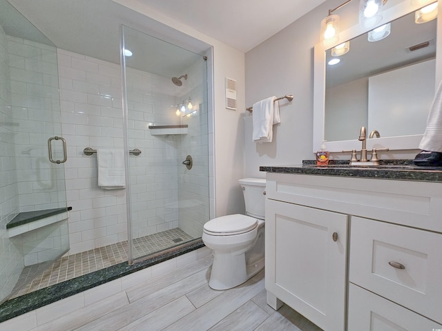 bathroom with vanity, a shower with shower door, and toilet