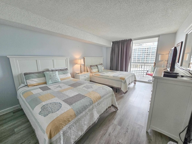 bedroom featuring wood-type flooring, a textured ceiling, and access to exterior