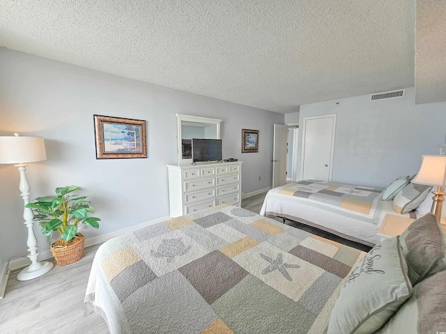 bedroom with a textured ceiling and light hardwood / wood-style flooring