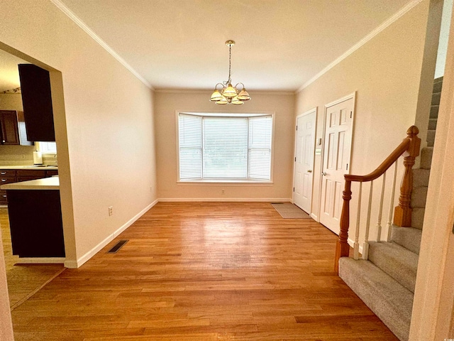 unfurnished dining area with an inviting chandelier, light hardwood / wood-style flooring, and ornamental molding