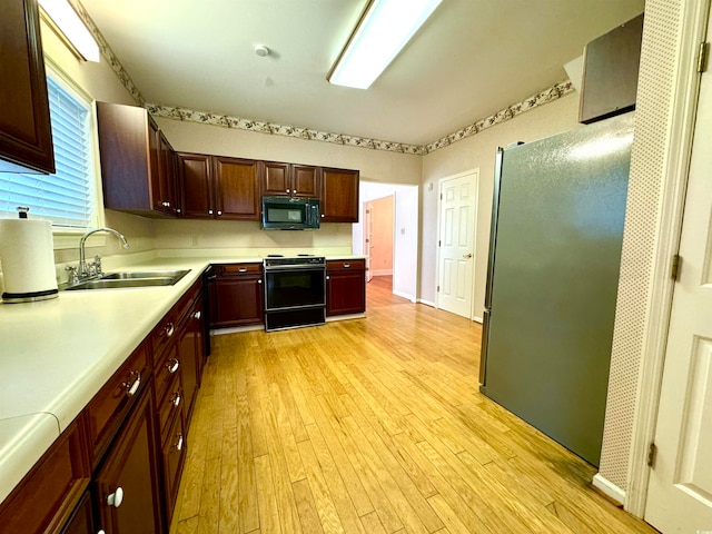 kitchen with sink, black appliances, and light wood-type flooring