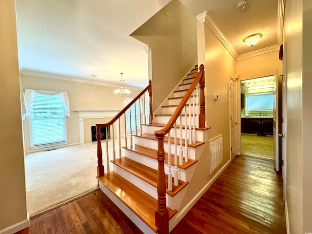 stairs with an inviting chandelier, sink, carpet, and ornamental molding