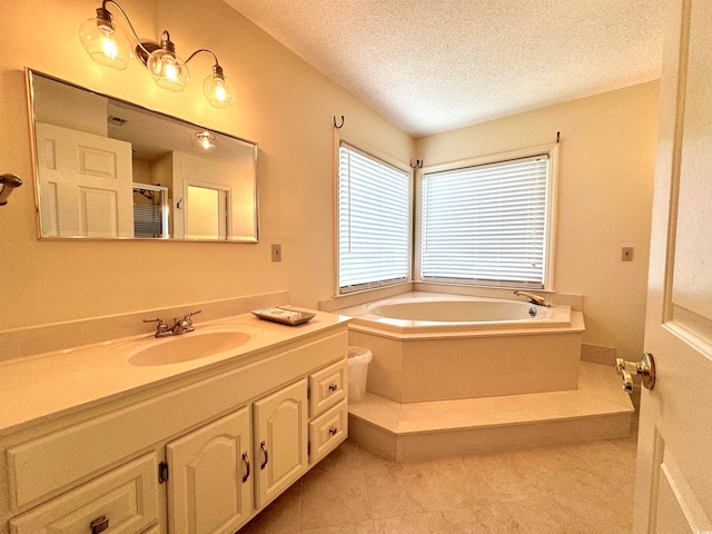 bathroom featuring vanity, a textured ceiling, a tub to relax in, and tile patterned flooring