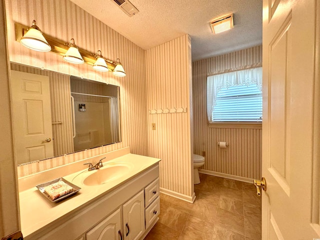 bathroom featuring vanity, toilet, tile patterned floors, and a textured ceiling